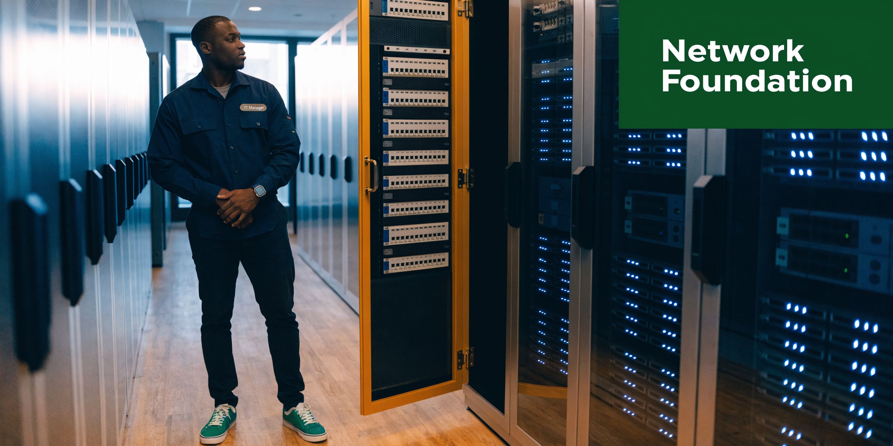 An IT manager stands in a modern server room, checking network equipment hardware in data center racks.