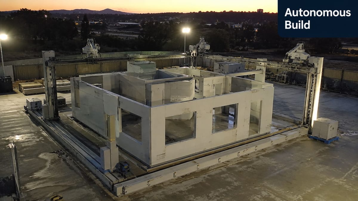 A large autonomous construction machine building the concrete walls of a house at sunset.