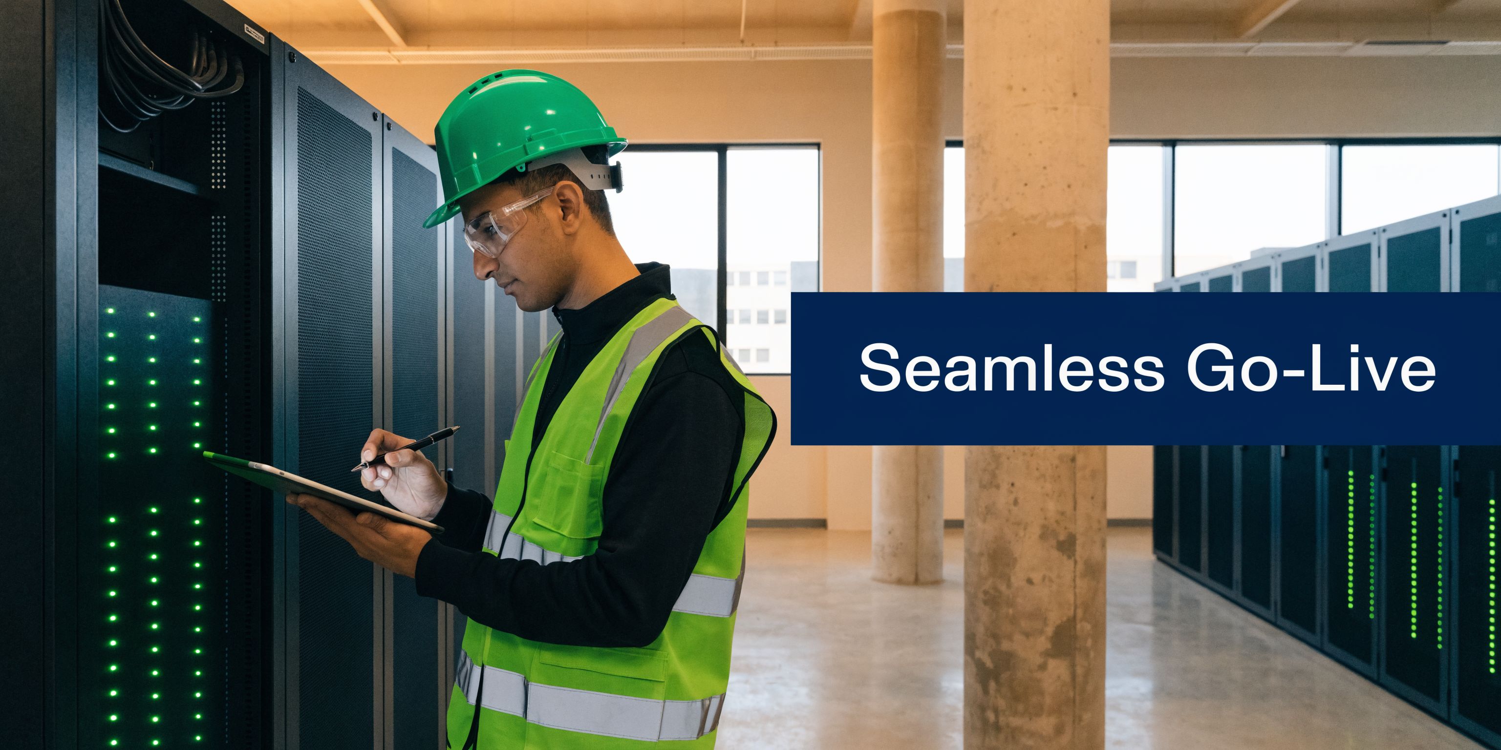 A technician wearing a safety helmet and vest checks server equipment using a tablet in a data center.